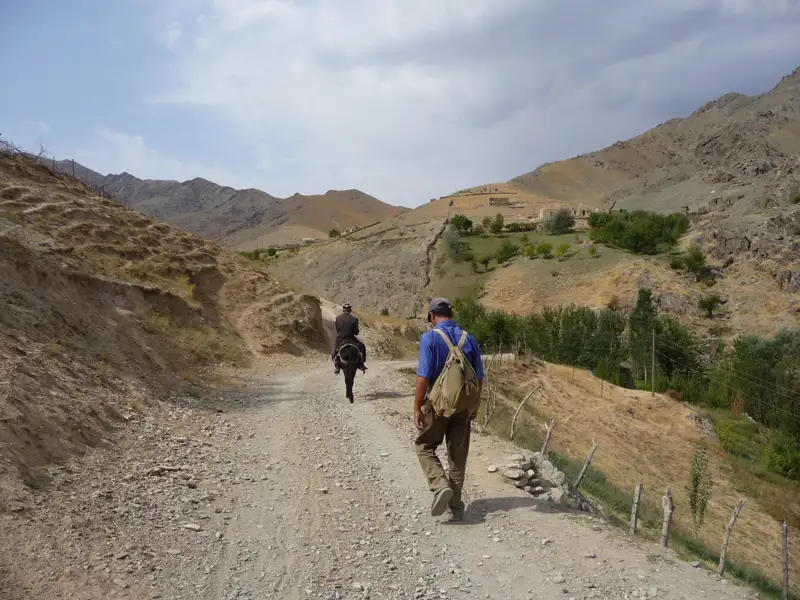 Wanderung auf einem Bergpfad: Ein Wanderer und ein Eselreiter auf dem Weg.