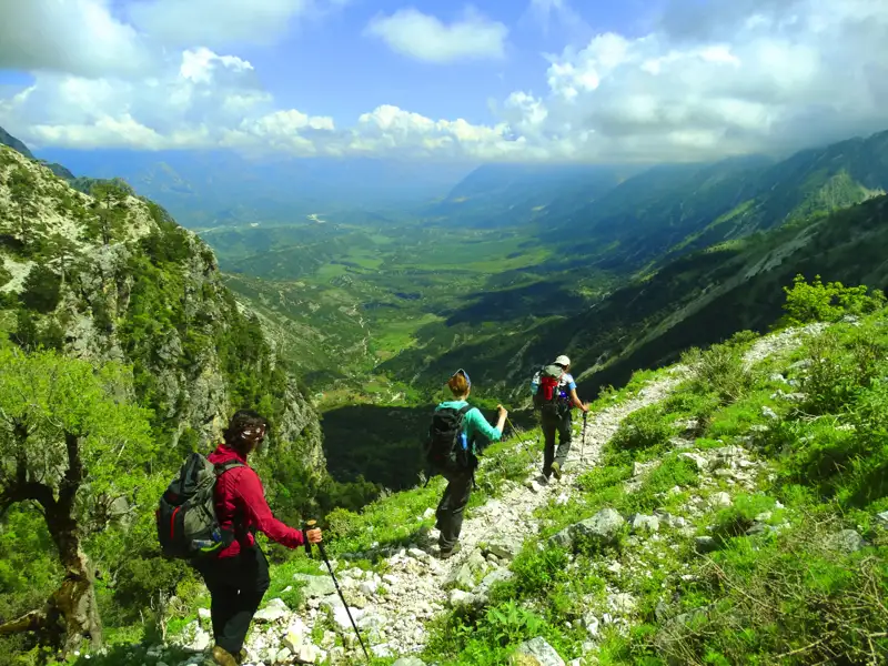Wanderer auf einem Bergpfad mit Blick auf ein Tal.