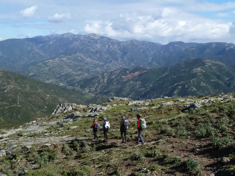 Wanderer mit Rucksäcken auf einem Bergpfad mit Blick auf die Bergkette.