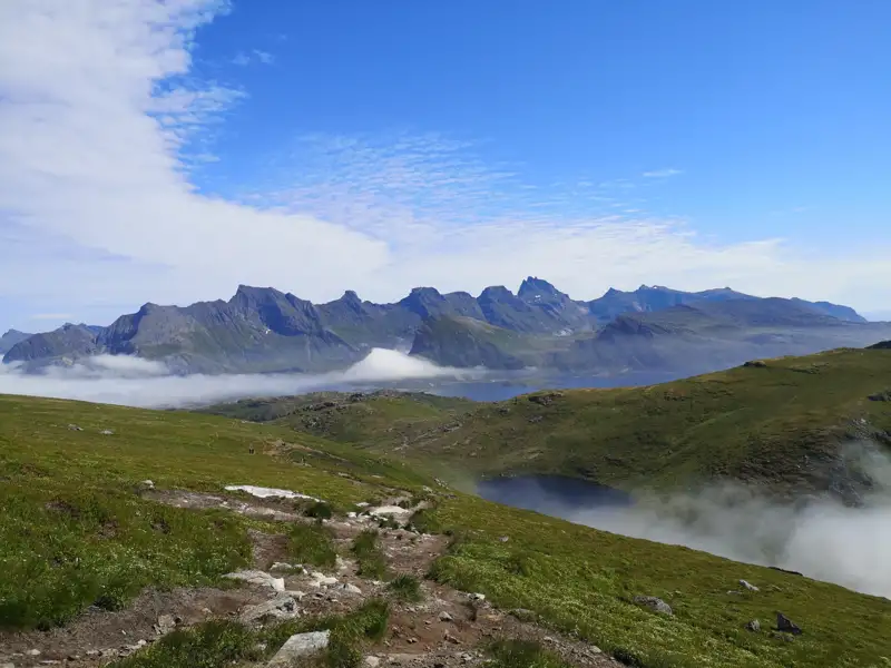 Wanderweg in den Bergen mit Wolken und Seen.