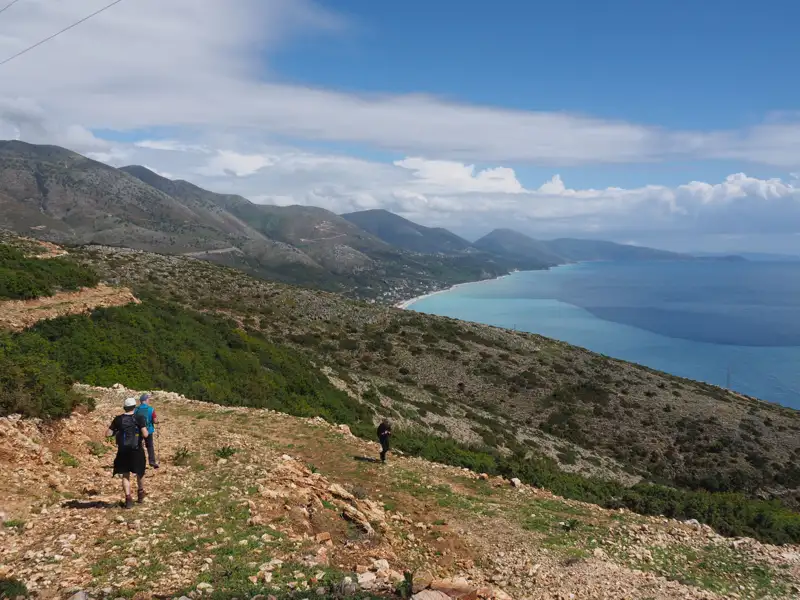 Wanderer auf einem Bergpfad mit Blick auf die Küste und das Meer.