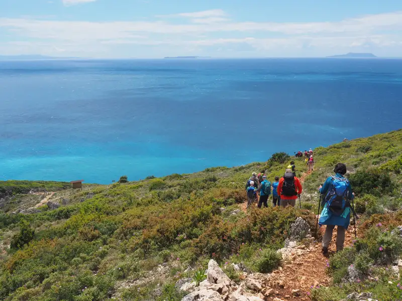 Wandergruppe auf einem Küstenpfad mit Blick auf das Meer.