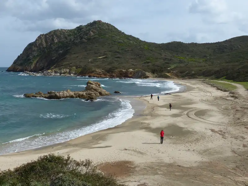 Abgelegener Strand mit Hügelkette im Hintergrund.