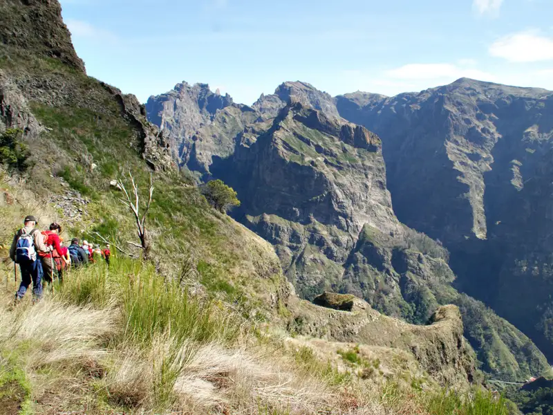 Wandergruppe auf einem Bergpfad inmitten einer beeindruckenden Berglandschaft.