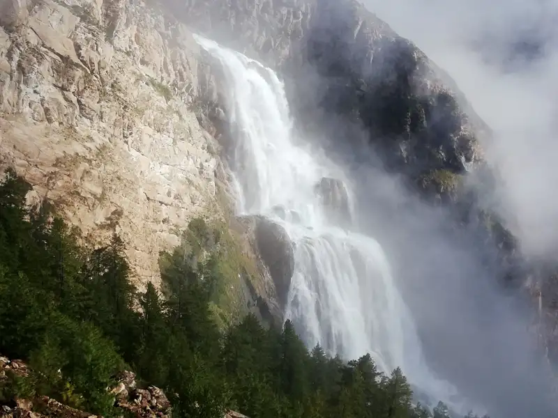 Wasserfall, der von einer Klippe stürzt und teilweise von Nebel verdeckt wird.