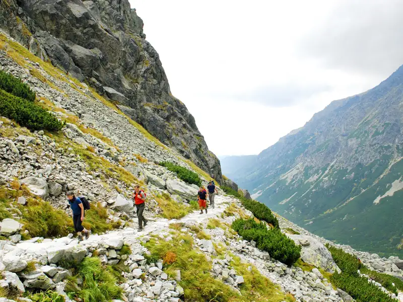 Wanderer auf einem Bergpfad in einer bergigen Landschaft.