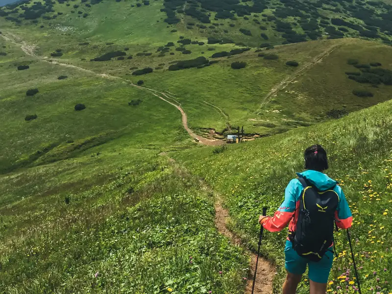 Wanderer mit Rucksack und Wanderstöcken auf einem Bergpfad.