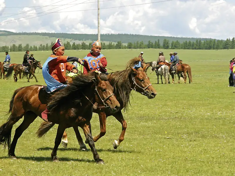 Junge Reiter in traditioneller Kleidung beim Pferderennen.