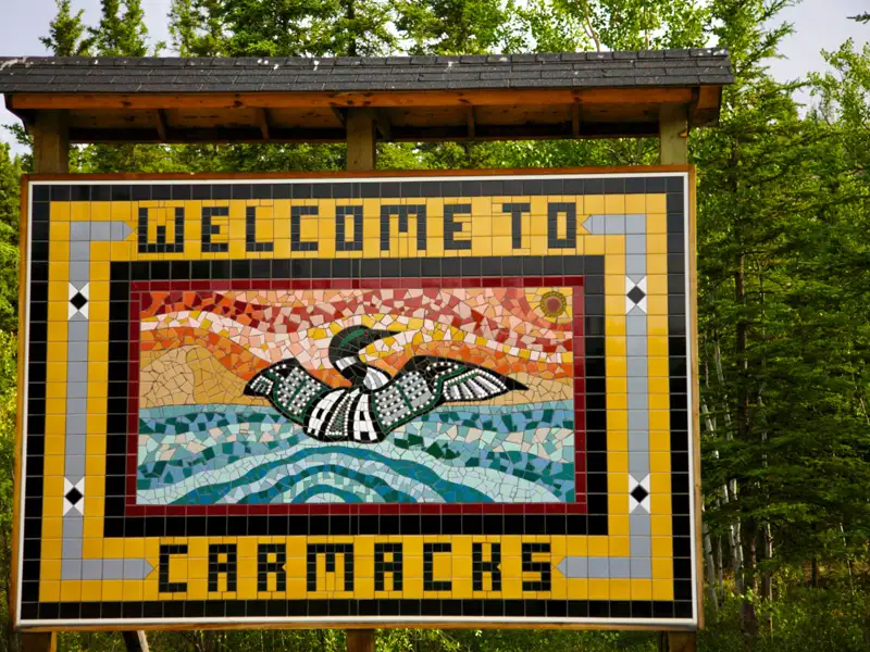 Willkommensschild aus Mosaikfliesen in Carmacks mit der Aufschrift 'Welcome to Carmacks' und einem Seetaucher.