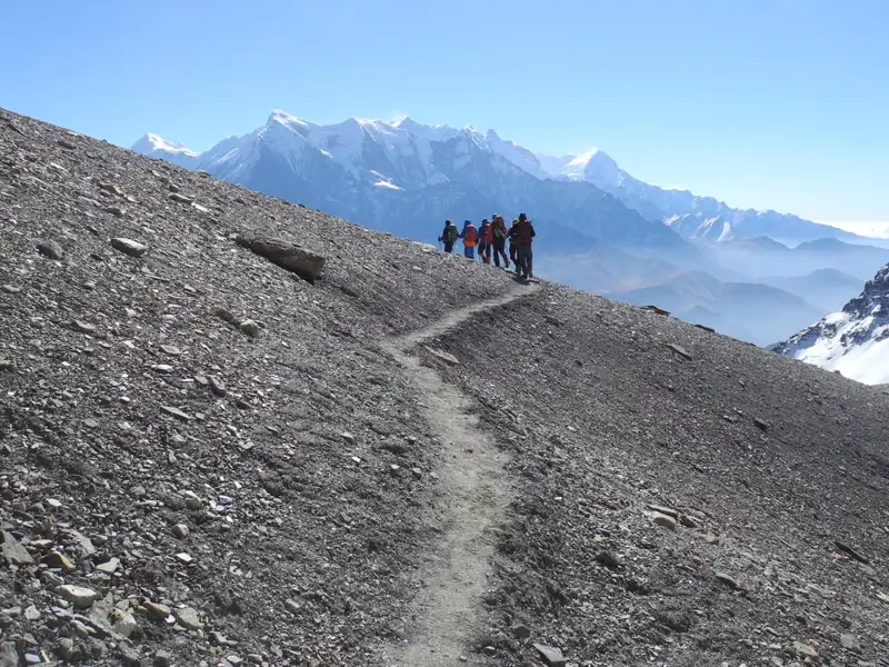Wanderer auf einem Bergpfad inmitten einer Gebirgslandschaft.