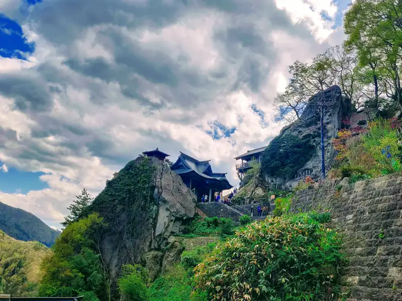 Ein Tempel in den Bergen, umgeben von Bäumen und Vegetation.