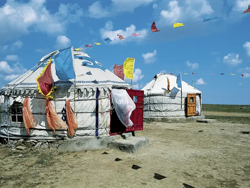Zwei Jurten dienen als Unterkunft, geschmückt mit traditionellen Fahnen.