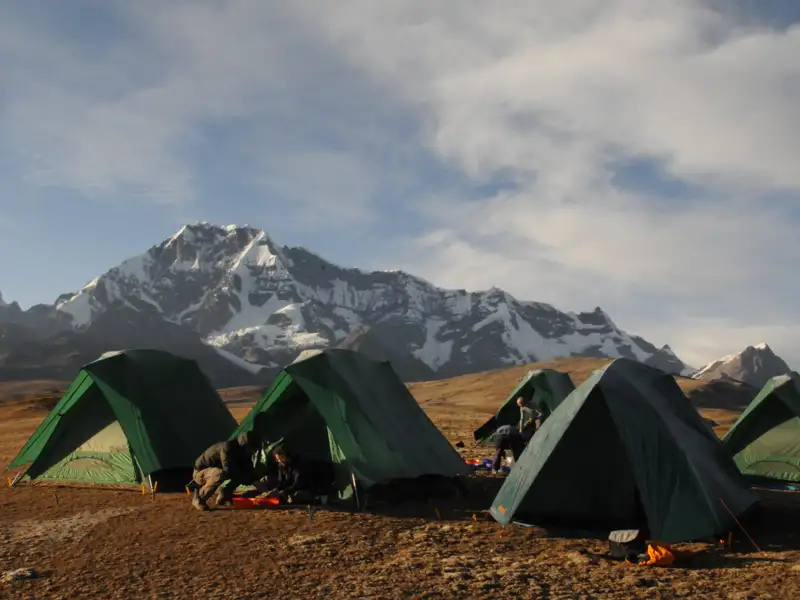 Zeltaufbau im Basislager vor einer Bergkulisse.