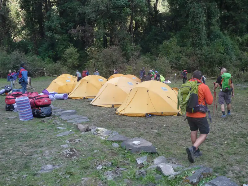 Wanderer auf einem Campingplatz mit Zelten und Ausrüstung.