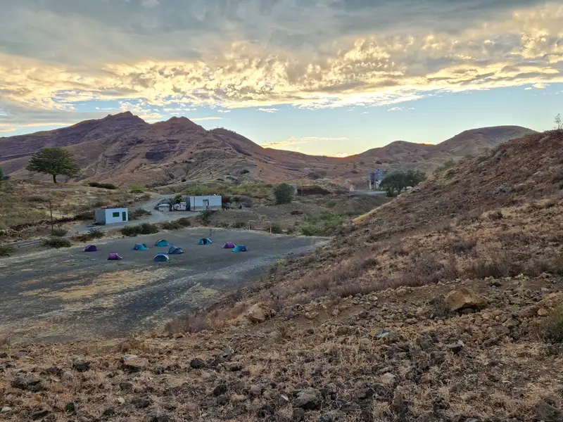 Campingplatz mit mehreren Zelten in einer bergigen Umgebung.