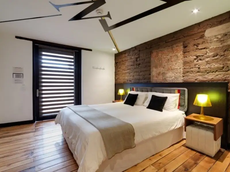 Blick auf das Schlafzimmer mit Doppelbett, Backsteinwand und Holzboden.