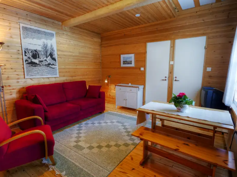 Wohnbereich des Ferienhauses mit Sofa, Tisch und Stühlen.