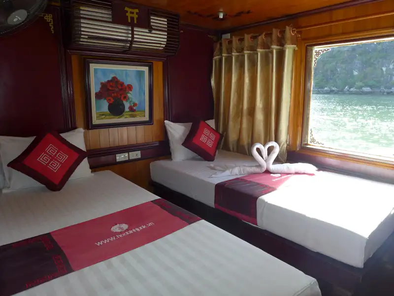 Innenansicht einer Kabine auf einem Kreuzfahrtschiff mit zwei Einzelbetten und Meerblick.