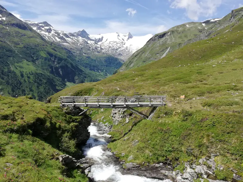 Holzbrücke über einen Gebirgsbach in den Alpen.
