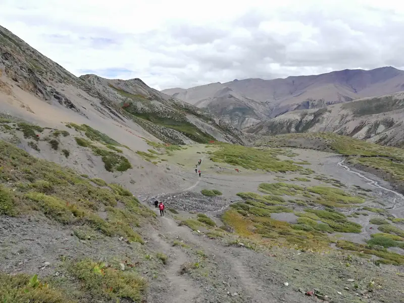 Wanderer auf einem Bergpfad in einer bergigen Landschaft.