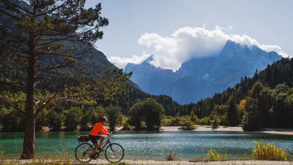 Radfahrer auf einer Tour entlang eines Bergsees mit Blick auf die Bergkette.