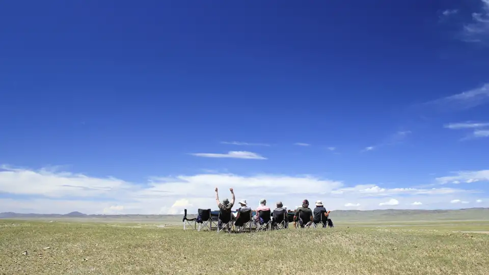 Reisende entspannen sich in Campingstühlen und genießen die Aussicht auf die weite Landschaft.