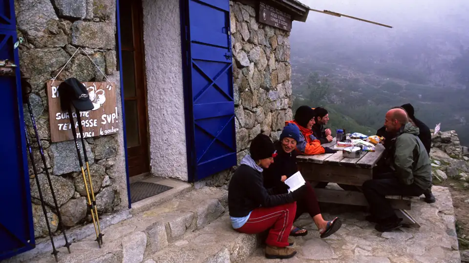 Wanderer pausieren an einer Berghütte und erfrischen sich.