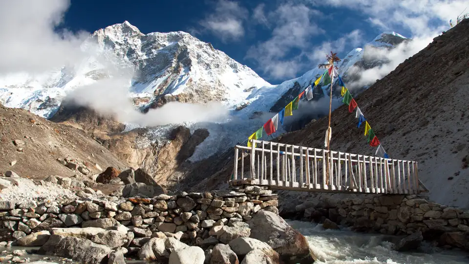 Holzbrücke mit Gebetsfahnen im Himalaya Gebirge.